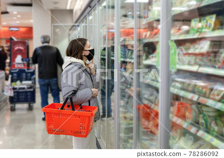 Caucasian woman in black face mask with red shopping basket 78286092