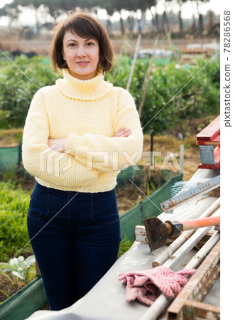 Girl in a yellow sweater in the backyard of her cottage Girl in a yellow sweater in the backyard of her cottage 78286568