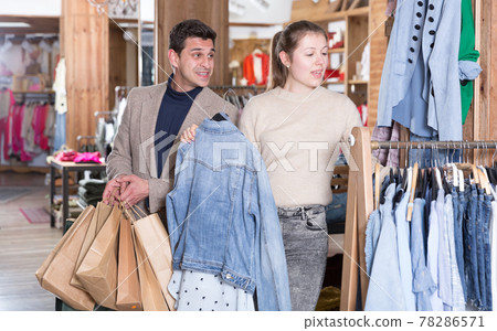 Smiling woman and man are choosing clothes and looking on jeans blouse 78286571