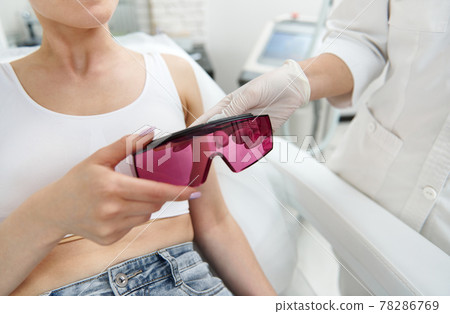 Close-up of protective UV goggles in female hands, for protect eyes during laser therapy in modern equipped beauty salon 78286769