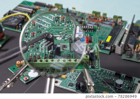A glass magnifier with a focus on electronic waste printed circuit Board. 78286949