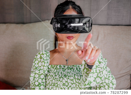 Asian Woman looking through virtual reality device at home. Augmented reality, game, future Asian Woman looking through virtual reality device at home. Augmented reality, game, future 78287299