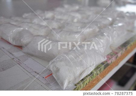A large number of transparent sachets filled with white powder. White powder packaged in small sachets. A large number of transparent sachets filled with white powder. White powder packaged in small sachets. 78287375