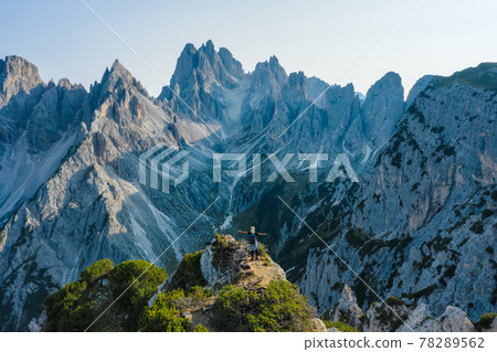 Aerial view of a women hiker with raised hands on the top edge admiring epic Cadini di Misurina mountain peaks, Italian Alps, Dolomites, Italy, Europe Aerial view of a women hiker with raised hands on the top edge admiring epic Cadini di Misurina mountain peaks, Italian Alps, Dolomites, Italy, Europe 78289562