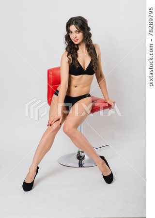 Cute brunette female model posing, wearing black and red underwear in white studio 78289798