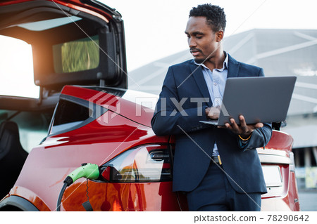 African businessman working on laptop and charging car African businessman working on laptop and charging car 78290642