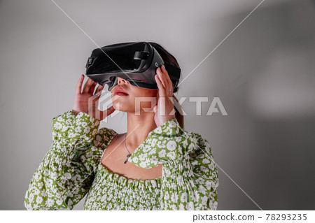 Asian Woman looking through virtual reality device at home. Augmented reality, game, future Asian Woman looking through virtual reality device at home. Augmented reality, game, future 78293235