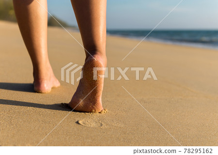 Close up of barefoot woman walking on the beach during sunset,Back view,Vacation and holiday concept 78295162
