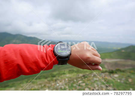 Hiker on high altitude mountain top checking the altitude on the sports watch Hiker on high altitude mountain top checking the altitude on the sports watch 78297795