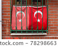 Two waving Turkish Flag in window with grate, brick wall 78298663