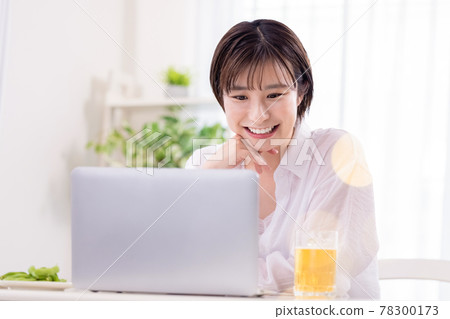 Portrait of a woman A young woman drinking beer while looking at a computer 78300173