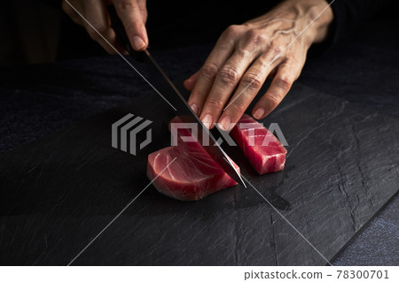 Female cook preparing a piece of bluefin tuna to make sushi. Asian food concept Female cook preparing a piece of bluefin tuna to make sushi. Asian food concept 78300701