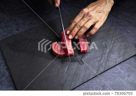Female cook preparing a piece of bluefin tuna to make sushi. Asian food concept Female cook preparing a piece of bluefin tuna to make sushi. Asian food concept 78300705