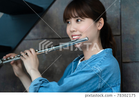 A woman blowing a flute A woman blowing a flute 78302175