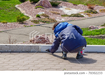 an employee paints the curb with white paint. city services, close-up an employee paints the curb with white paint. city services, close-up 78302233