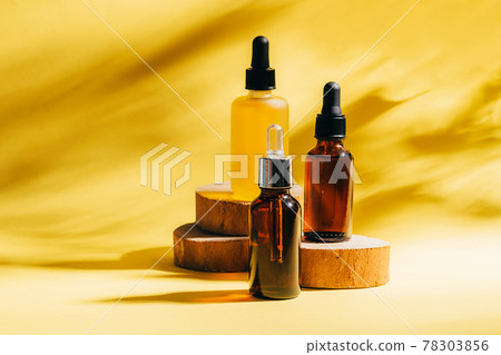 Cosmetics for face body for SPA procedures. Aromatherapy essential oil gel serum on wooden podiums yellow background 78303856