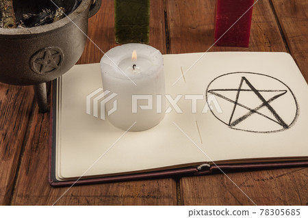 A candle, a witch's cauldron, and a pentacle in a book of shadows 78305685