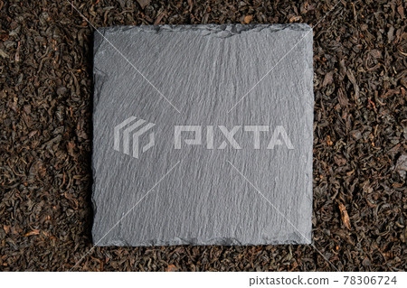 A slate in the shape of a square against the background of black tea. Top view. Copy space. 78306724
