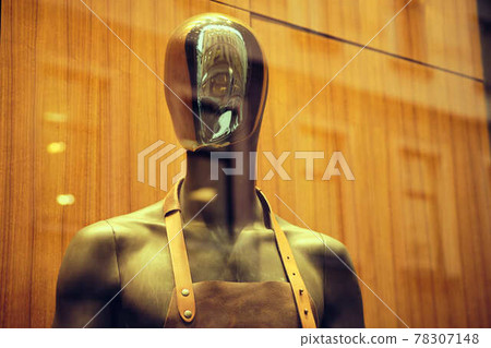 Stylish black mannequin in an apron on a store window. Stylish black mannequin in an apron on a store window. 78307148
