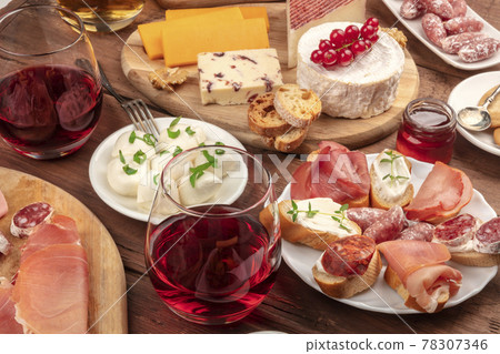 Wine tasting and pairing. A wineglass with sandwiches and a cheese platter Wine tasting and pairing. A wineglass with sandwiches and a cheese platter 78307346