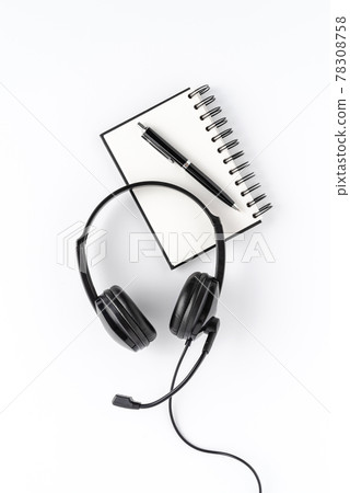 Helpdesk headset with notebook and pen on white desktop. Call center concept. Top view 78308758