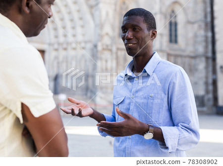 Friendly African American talking to passerby on city street 78308902