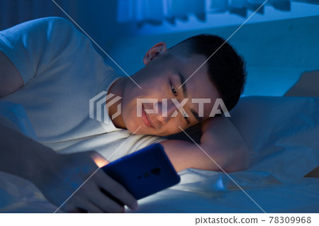 man use smartphone on bed 78309968