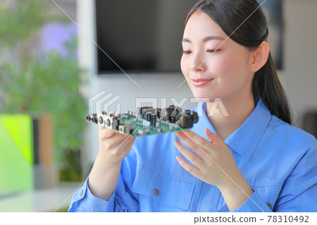 Engineer checking the board on which the semiconductor is mounted 78310492