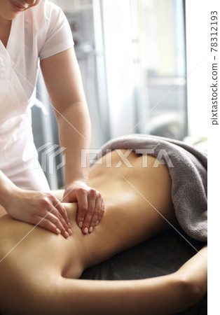 Masseur rubbing back of woman Masseur rubbing back of woman 78312193
