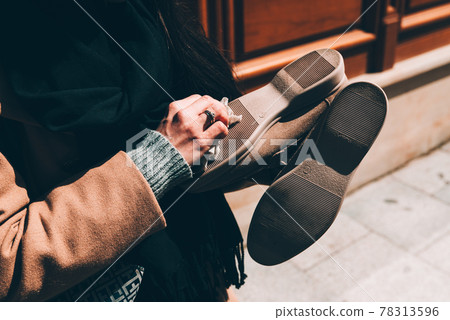 Someone cleaning shoes with his hands. woman wipes the sole of the shoe with a damp cloth 78313596