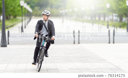 A young man in a suit running on a bicycle A young man in a suit running on a bicycle 78314173