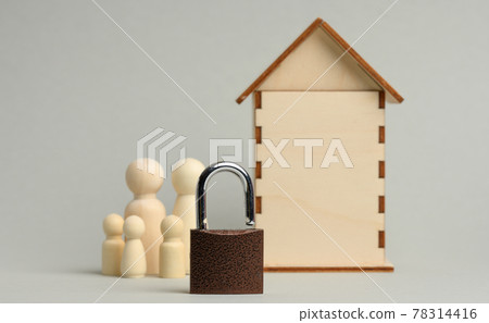 metal padlock on the background of a wooden miniature house and wooden figures of a family on a gray background. metal padlock on the background of a wooden miniature house and wooden figures of a family on a gray background. 78314416