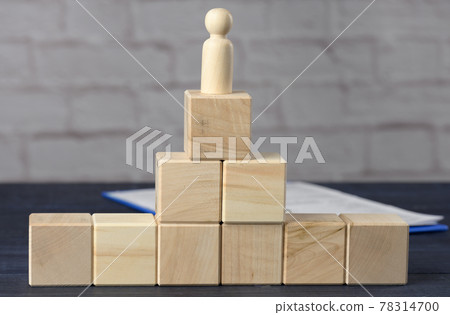 wooden figurine of a man on top of wooden cubes. The concept of purposefulness, achieving goals 78314700