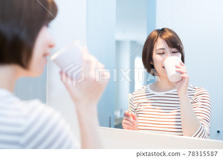 Young woman gargling in front of the mirror Young woman gargling in front of the mirror 78315587