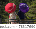A couple holding hands while holding an umbrella on a bridge in a Japanese garden 78317690