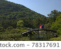 A couple looking at the scenery while holding an umbrella on the bridge in the Japanese garden 78317691