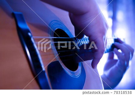 A man in a plaid cowboy shirt plays country music on a western dreadnought guitar. A man in a plaid cowboy shirt plays country music on a western dreadnought guitar. 78318538