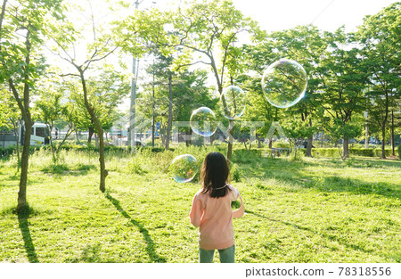 一個女孩在公園玩肥皂泡。 一個女孩在公園玩肥皂泡。 78318556