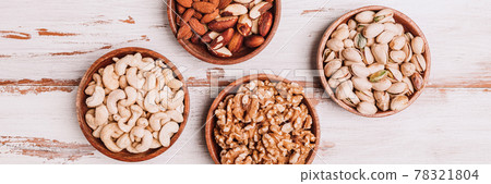 Different kind of nuts in wooden bowls Different kind of nuts in wooden bowls 78321804