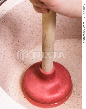 man clears water blockage in pink sink by plunger 78324047
