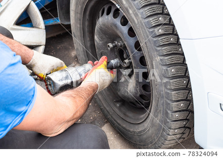 technician screws a car wheel by pneumatic wrench 78324094
