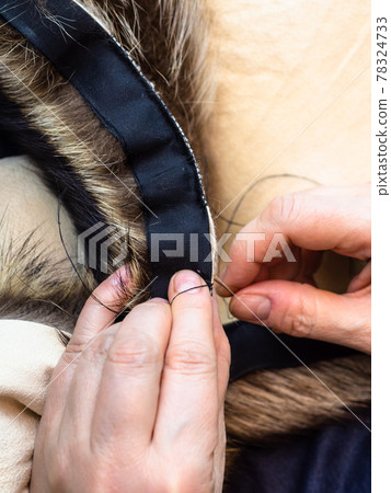 craftsman sews fur pelts by needle close up 78324733