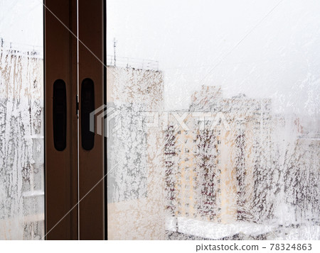 frozen window in urban house in city in winter 78324863