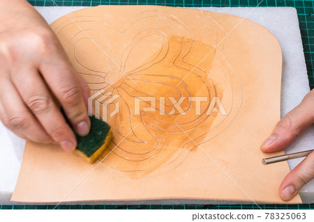 craftsman dampens the ornament on leather 78325063