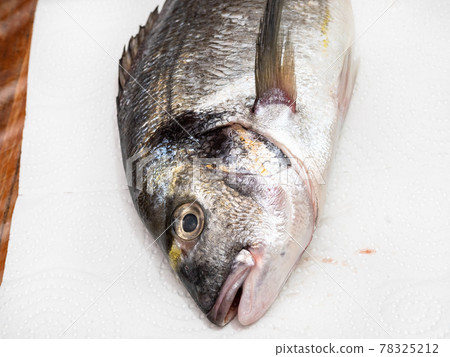 head of gilt-head bream (Orata) on paper on table 78325212
