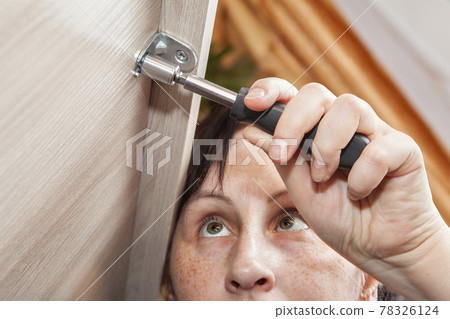 Self assembly of furniture from flat packing, woman tightens fastening nut. Self assembly of furniture from flat packing, woman tightens fastening nut. 78326124