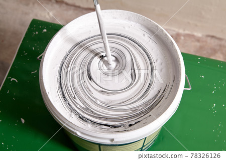 Adding black pigment to white wall paint for mixing in bucket using an electric mixer until gray color is obtained. Adding black pigment to white wall paint for mixing in bucket using an electric mixer until gray color is obtained. 78326126