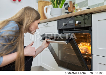 Young woman putting marinated chicken in baking bag in oven 78338488