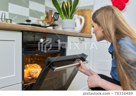 Young woman putting marinated chicken in baking bag in oven 78338489