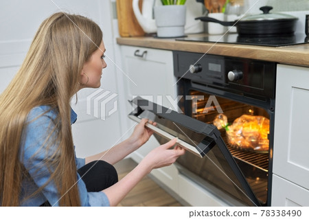 Young woman putting marinated chicken in baking bag in oven 78338490